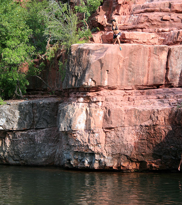 Girl cliff jumping into the water in Oak Creek Canyon